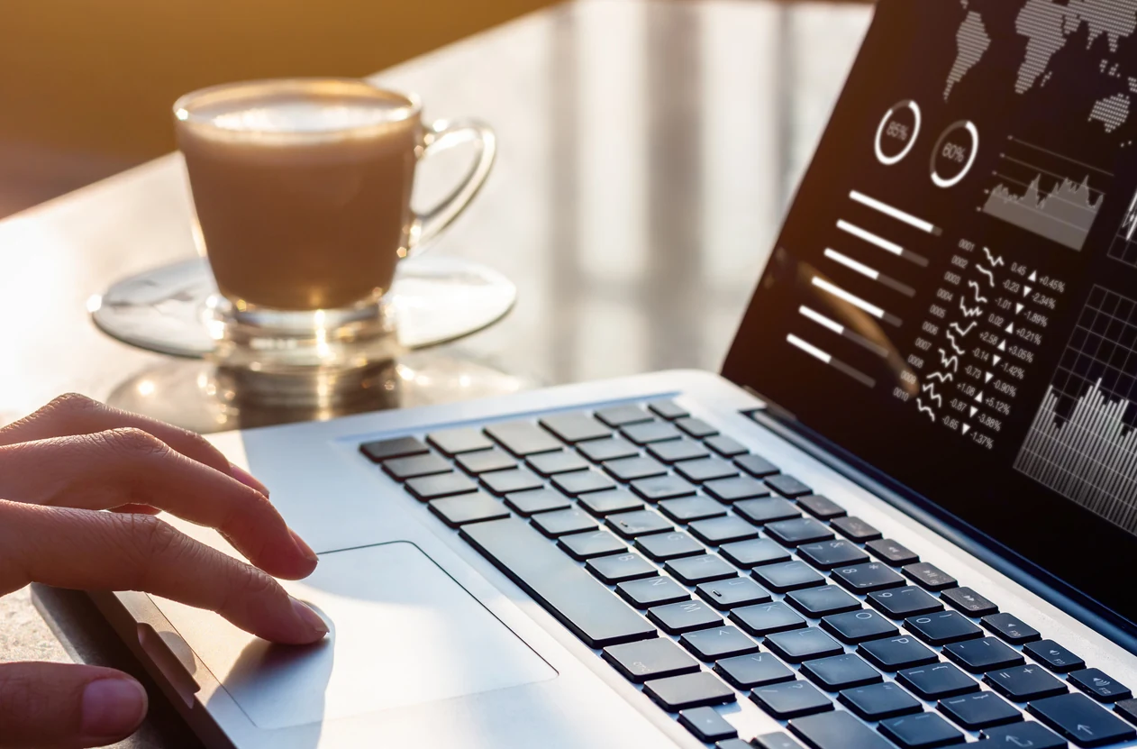 Manos sobre una laptop con gráficas de análisis de datos