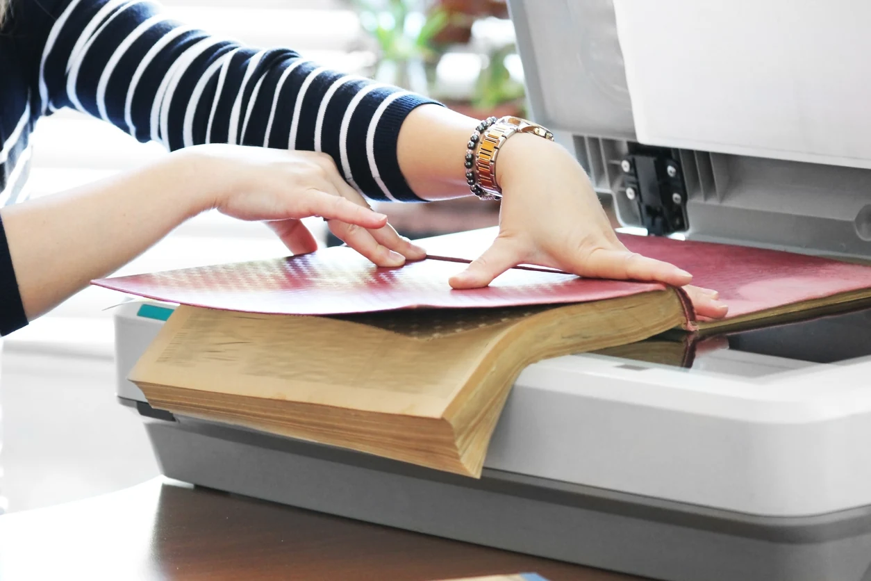 Manos con guantes digitalizando un libro en un escáner